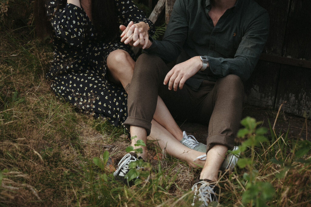 Caroline et fabien assis dans l'herbe, jambes entremêlées pour une séance photo.